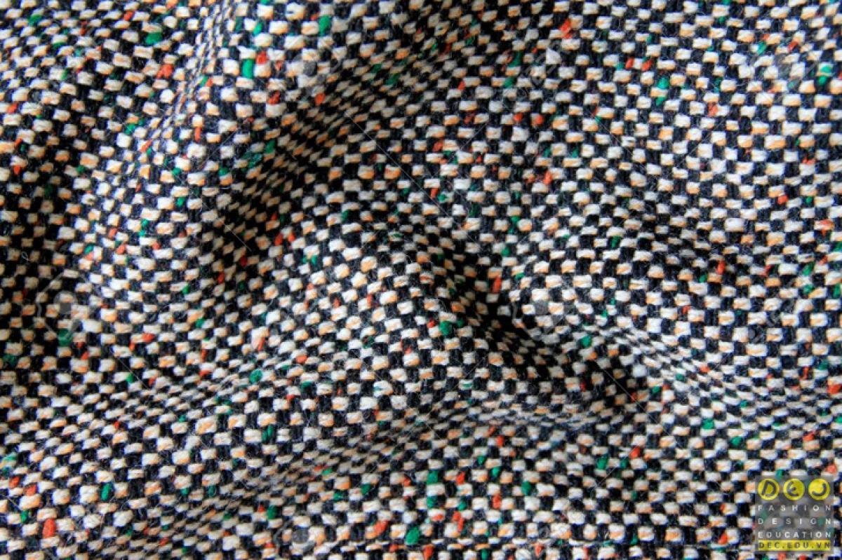 Cận cảnh chất liệu vải tweed cao cấp trên một chiếc áo khoác, thể hiện sự tinh xảo trong từng đường may đặc trưng của thời trang sang trọng.